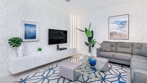 Een moderne woonkamer met een flatscreen televisie, een bank, een salontafel en een kamerkleed met dessin.