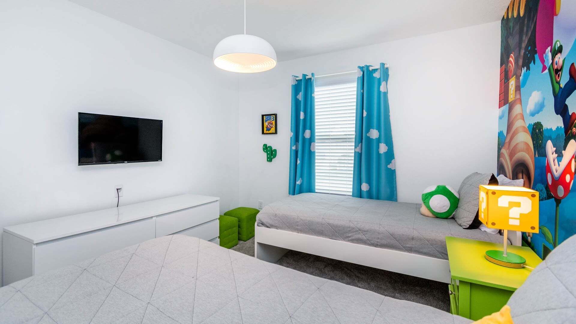Ein Schlafzimmer mit Bett, Fernseher, Schreibtisch und Wandgemälde.