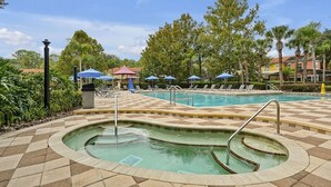 A swimming pool with a checkered tile pattern, lounge chairs, and umbrellas. - 8567 BAY Lily Loop, 3 BED (Kissimmee)