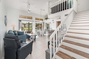 A spacious living area with a staircase, a dining table, and a sofa. - 8702 Papaya DR, 2bed (Kissimmee)