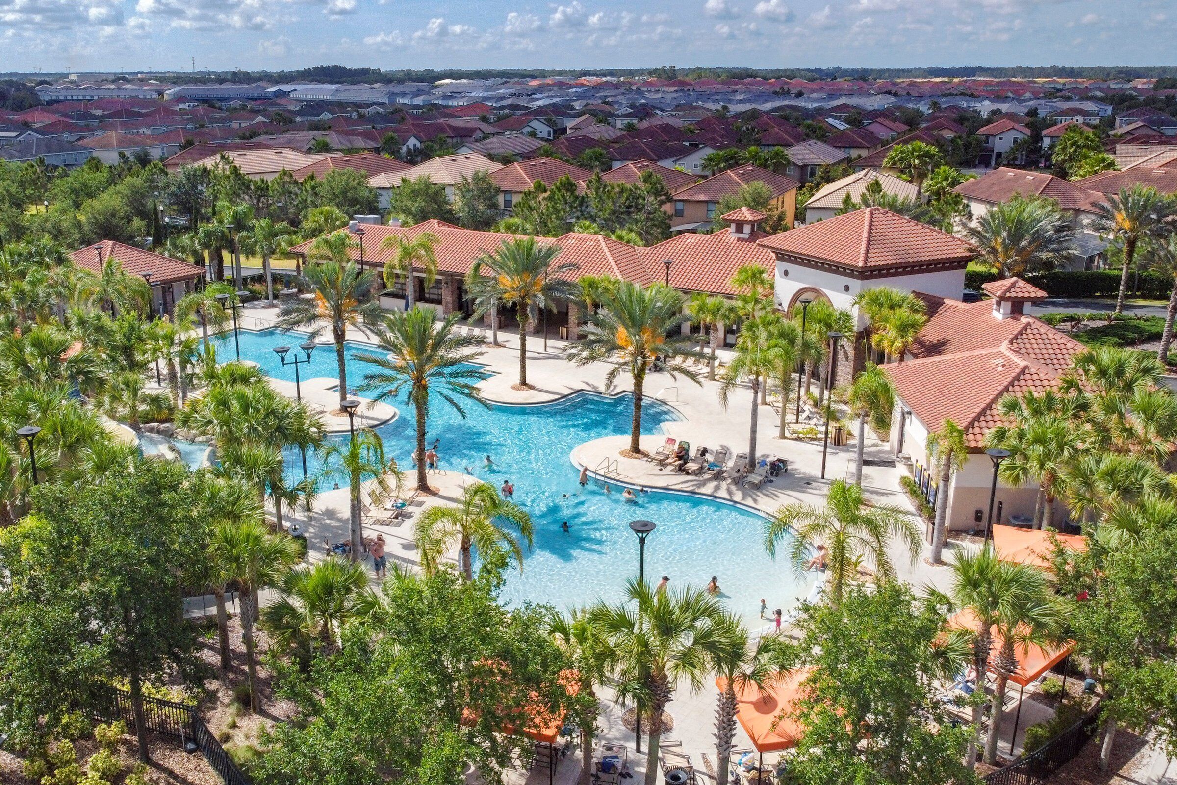 A resort with a central swimming pool surrounded by palm trees and lounge areas.