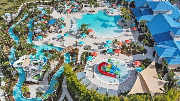 Luftaufnahme eines Resorts mit einem zentralen Swimmingpool, mehreren Wasserrutschen und Liegestühlen.