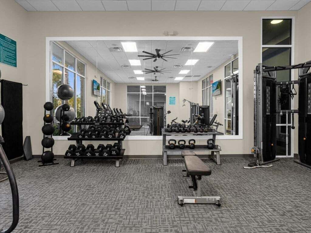 A gym with various exercise equipment, including dumbbells, a bench, and weight machines.