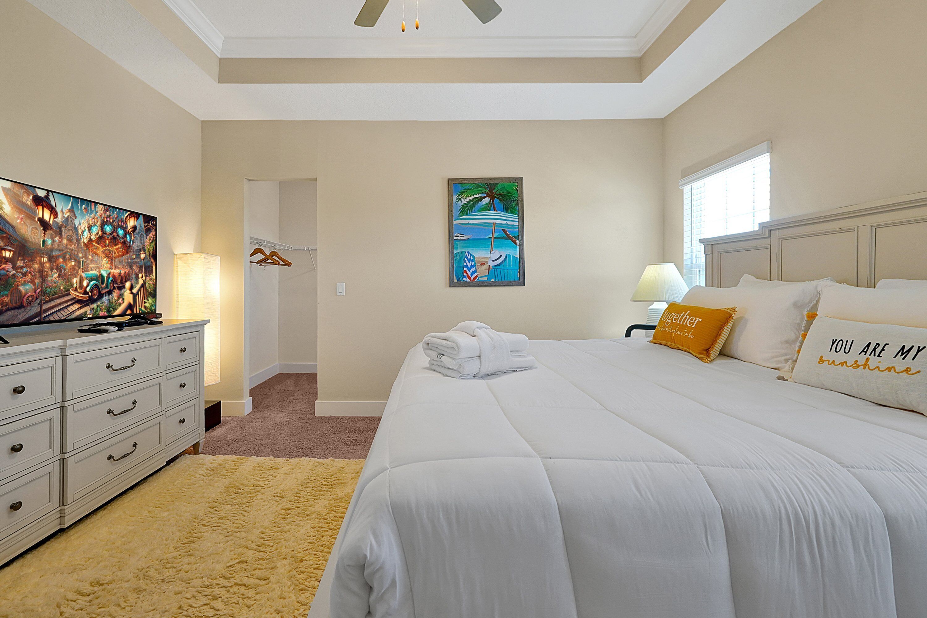 A hotel room with a large bed, a TV, a painting, and a window.