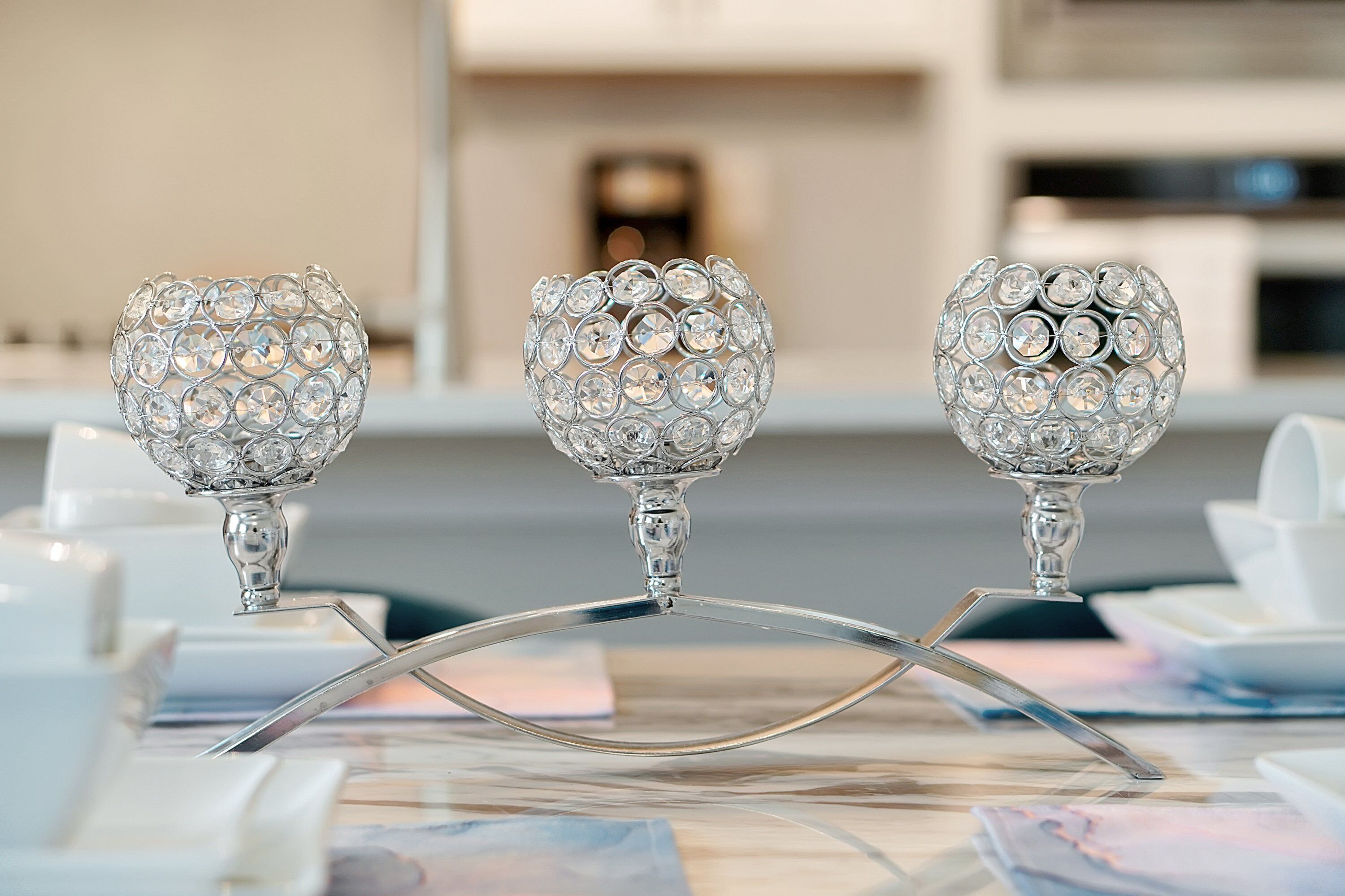 Trois chandeliers décorés de cristaux, posés sur une table.