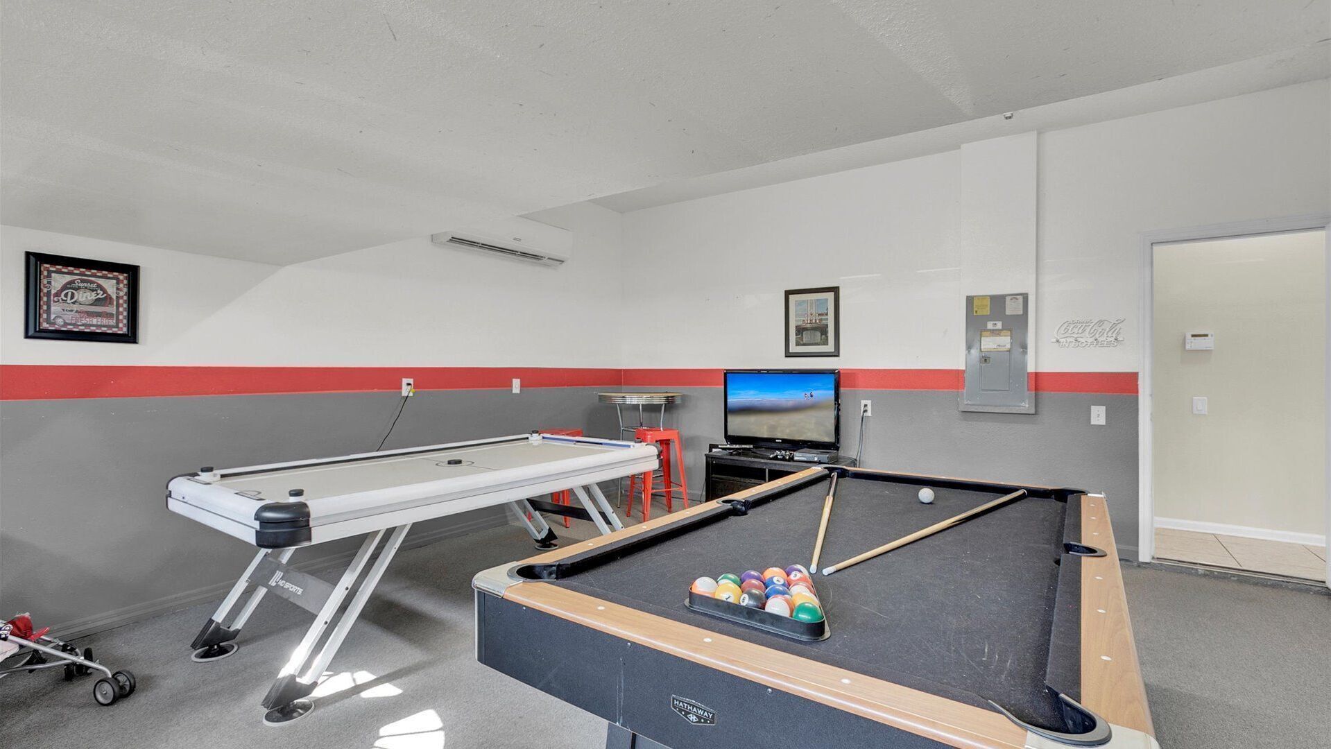 A pool table with balls, a television, and a framed picture on the wall.