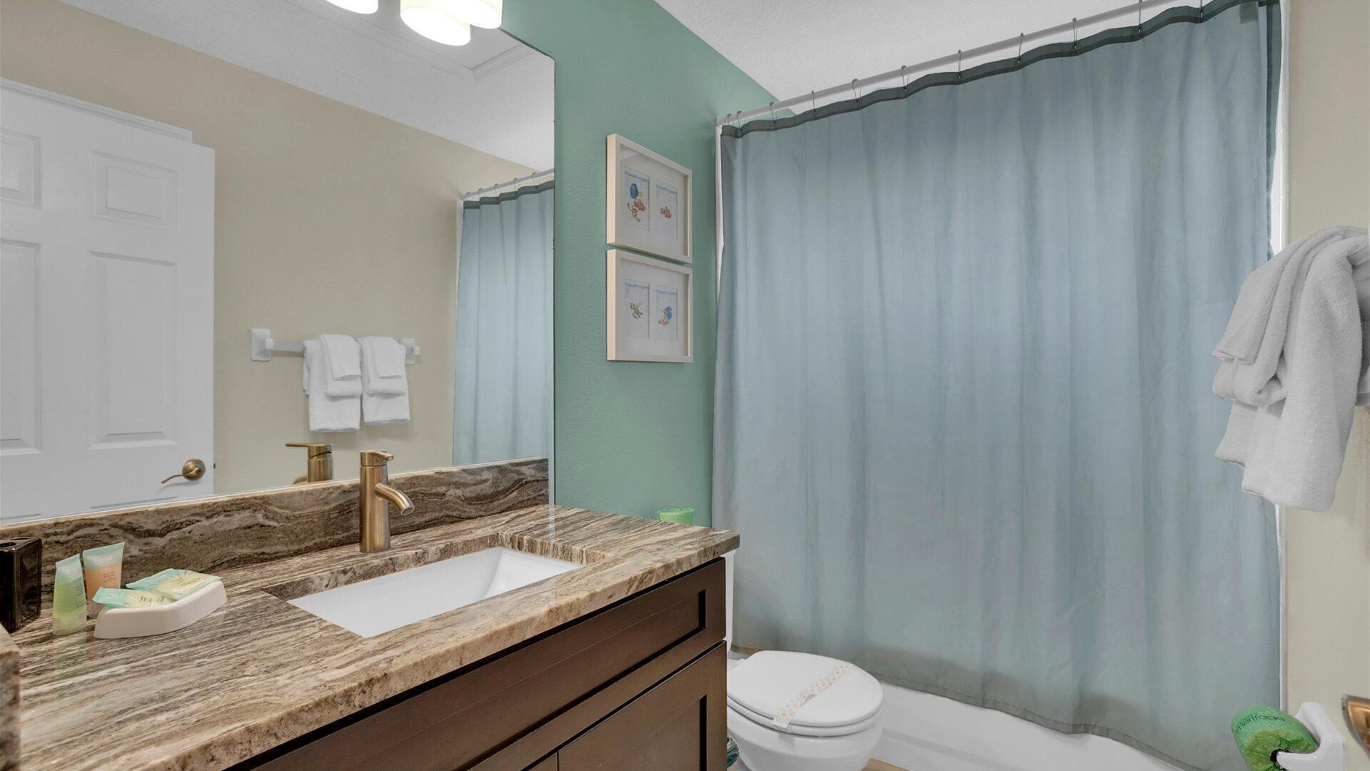 A bathroom with a marble sink, a white toilet, and a shower curtain.
