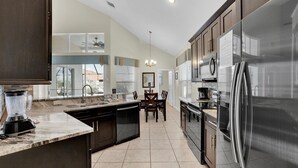 Una cocina moderna con armarios oscuros, una isla grande y electrodomésticos de acero inoxidable.