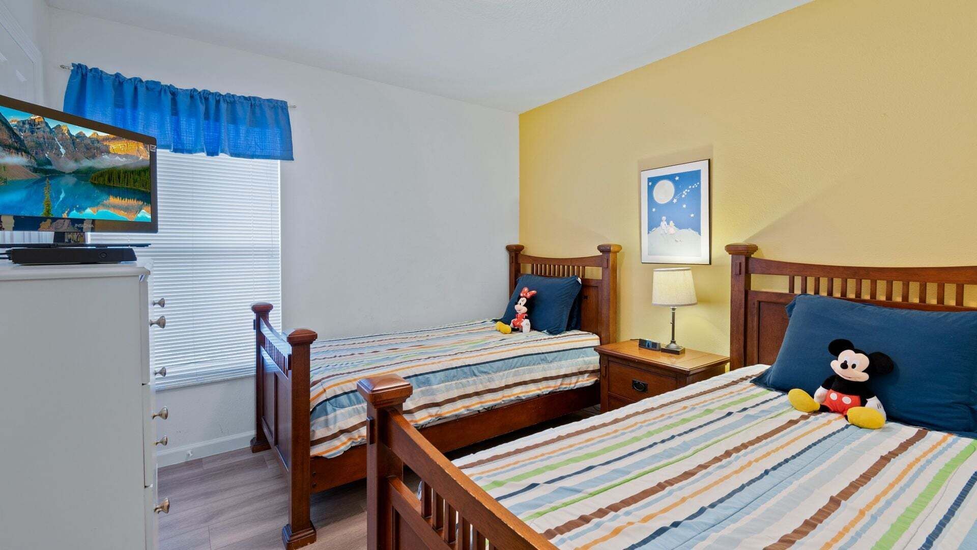 A hotel room with two beds, a TV, a desk, and a nightstand.