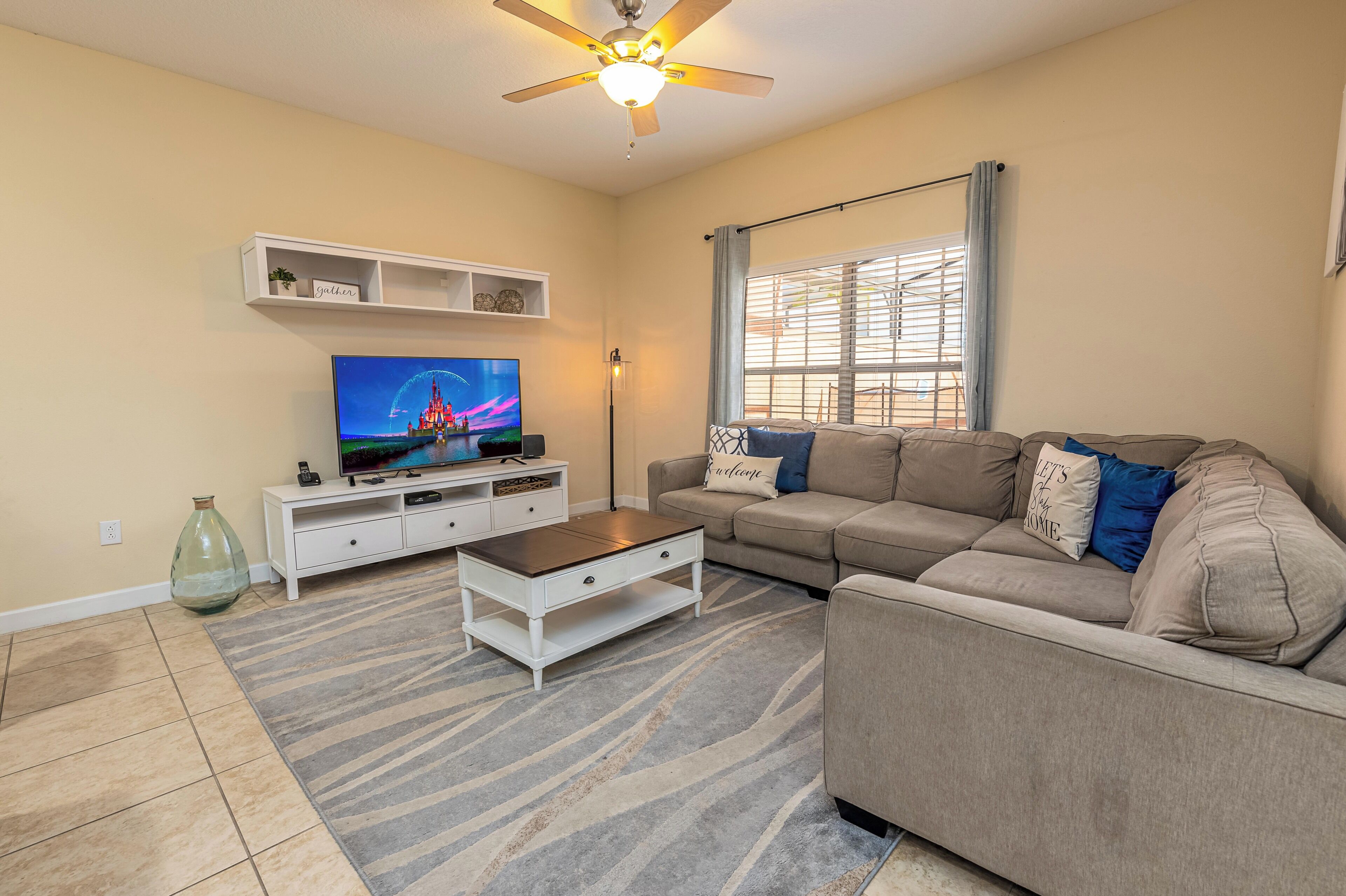A living room with a television, sofa, coffee table, and a ceiling fan.