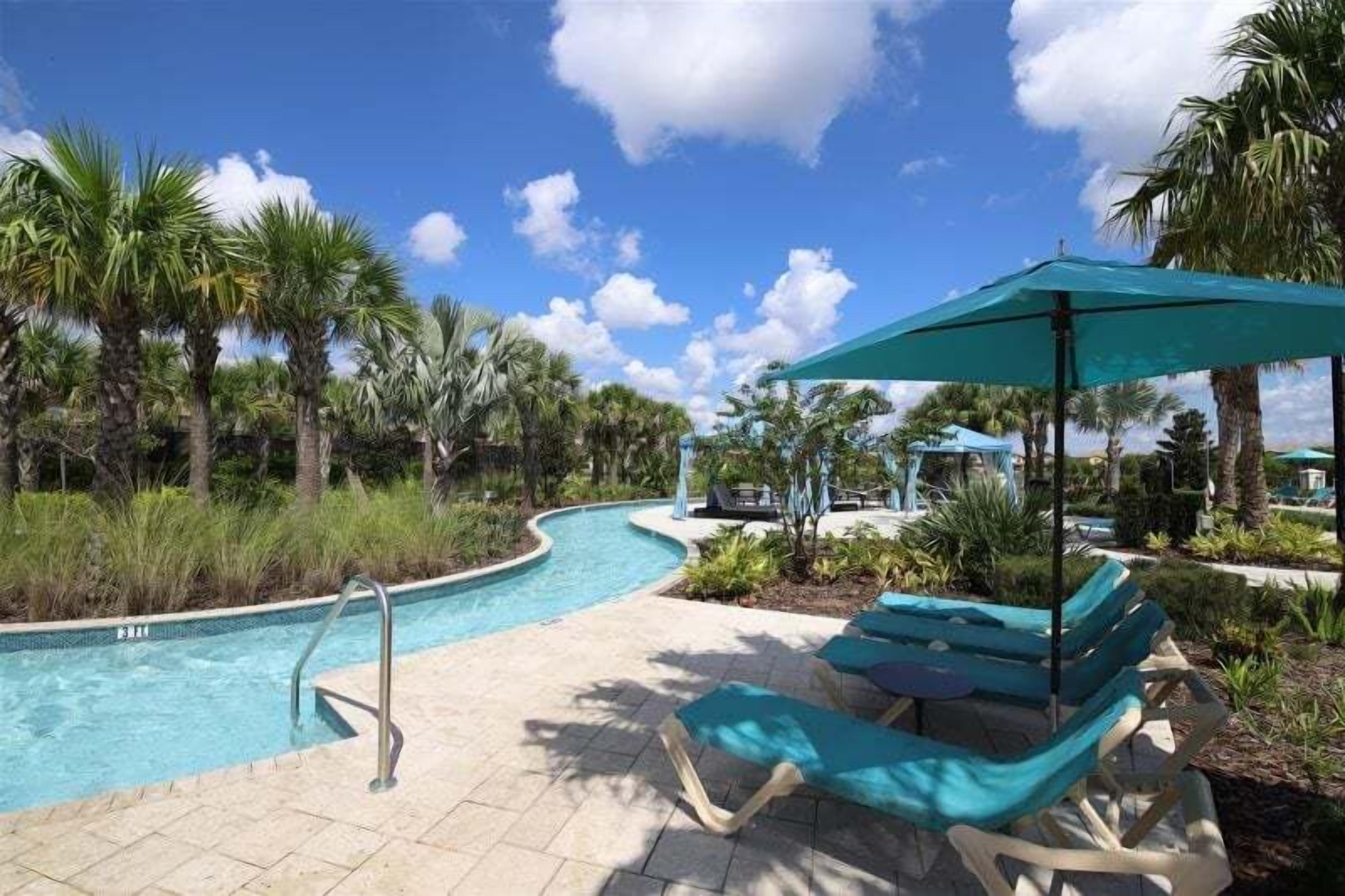 A pool area with lounge chairs and umbrellas, surrounded by palm trees.