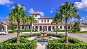 A building with a fountain, palm trees, and a car parked in front. - Flash 20 Off Amazing New Townhome With Pvt Pool and Access to Clubhouse Close to Disney (Kissimmee)