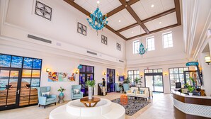 A spacious lobby with a round seating area, a reception desk, and large windows offering views of the ocean. - Flash 20 Off Amazing New Townhome With Pvt Pool and Access to Clubhouse Close to Disney (Kissimmee)