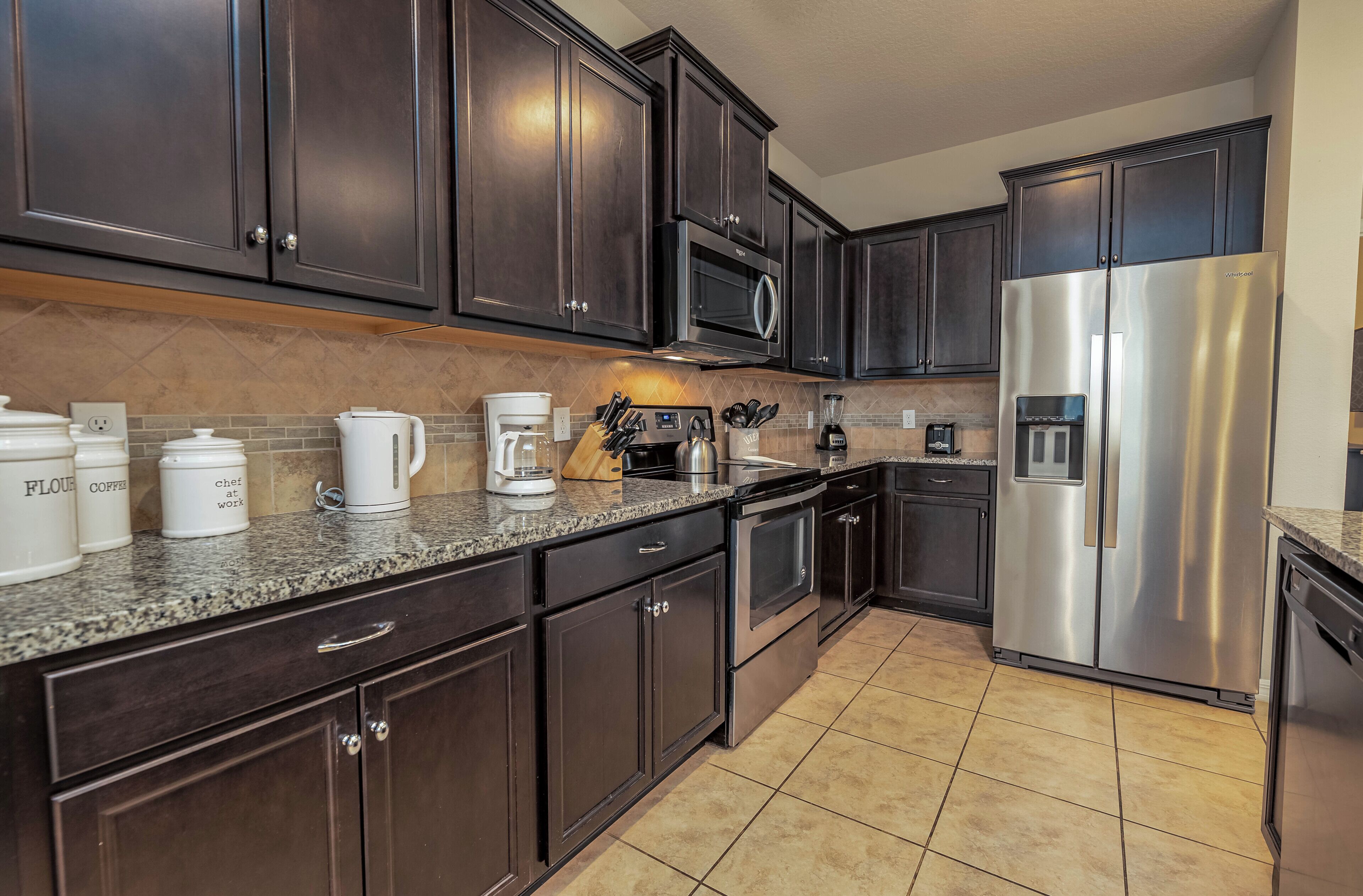 A kitchen with dark wooden cabinets, stainless steel appliances, and a granite countertop.