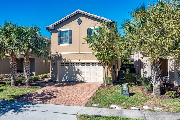 A two-story house with a garage, surrounded by palm trees and a brick driveway. - Flash 20 Off Private Pool Home at Windsor at Westside Resort (Kissimmee)