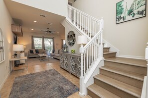 A spacious living area with a staircase, a sofa set, a coffee table, a side table, and a decorative cabinet. - Flash 20 Off Private Pool Home at Windsor at Westside Resort (Kissimmee)