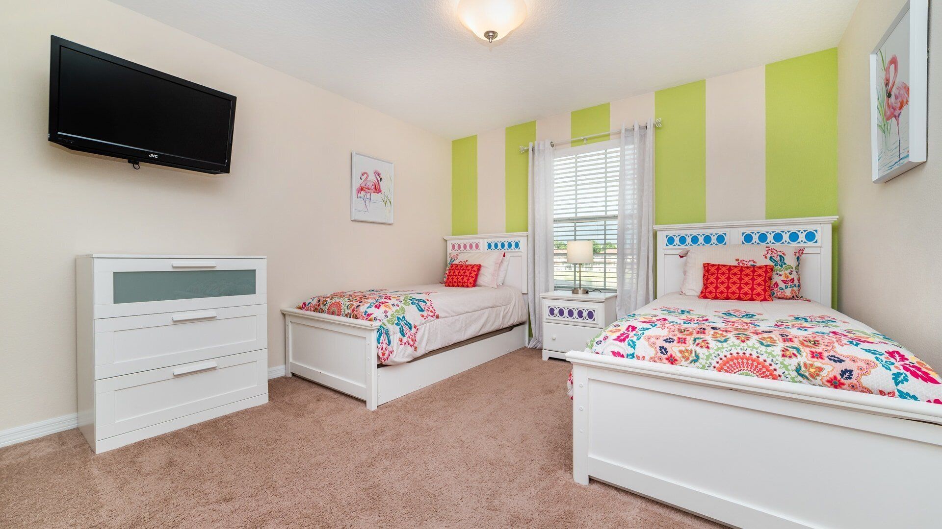 A bedroom with two beds, a TV, a dresser, and a window with blinds.