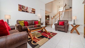A living room with a sofa, armchairs, a coffee table, a rug, and a staircase. - Bnc7795 (Kissimmee)