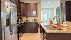 A modern kitchen with dark wood cabinets, stainless steel appliances, and a granite countertop. - 7613-8-bl-only 10 Minutes From Disney (Kissimmee)