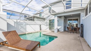 Ein modernes Haus mit Schwimmbad, Gartenmöbeln und einer Terrasse.