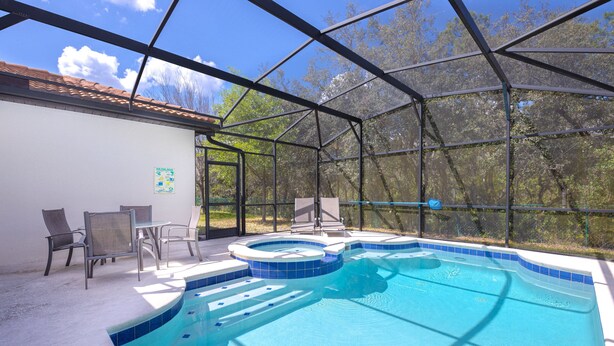 Ein überdachter Swimmingpool mit Whirlpool, Stühlen und einem Tisch.
