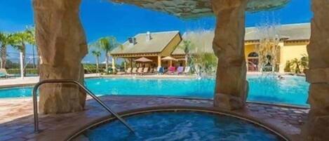 A hot tub area with a pool and a building in the background.