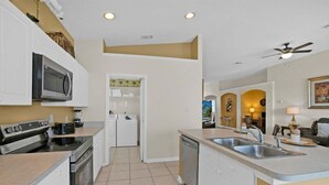 A compact kitchen with a microwave, stove, dishwasher, and a small sink. - Fp8190 Windsor Palms Resort Vacation Home (Kissimmee)