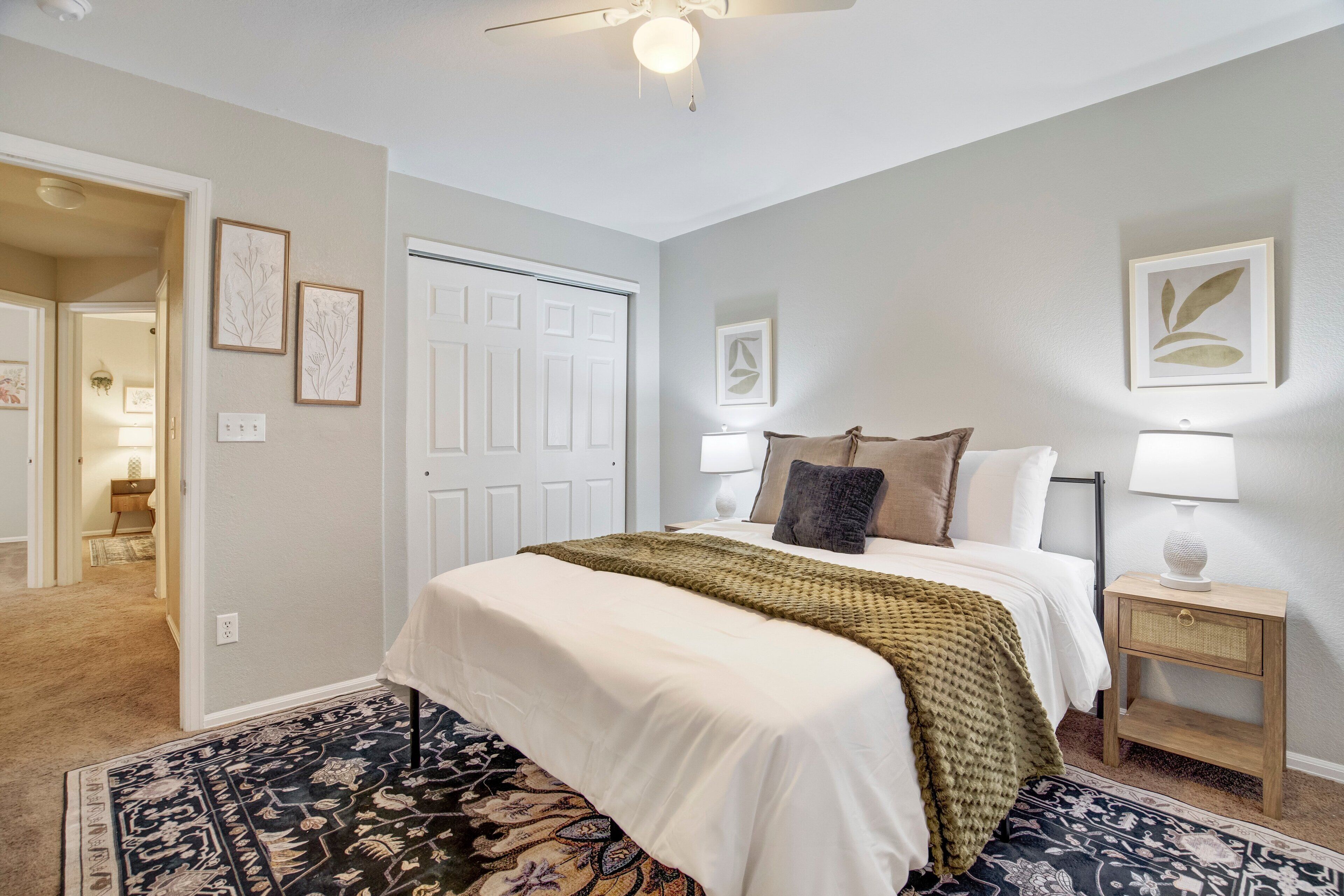 A bedroom with a bed, bedside lamps, a nightstand, and a door.