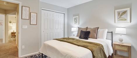 A bedroom with a bed, bedside lamps, a nightstand, and a door.