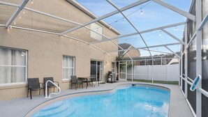 An outdoor swimming pool with a covered patio area, chairs, and a grill. - Rgc346 (Davenport)