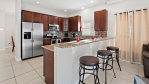 A modern kitchen with a central island, stainless steel appliances, and dark wooden cabinets. - Rgc346 (Davenport)
