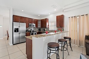 A modern kitchen with a central island, stainless steel appliances, and dark wood cabinets. - Rgc346 (Davenport)