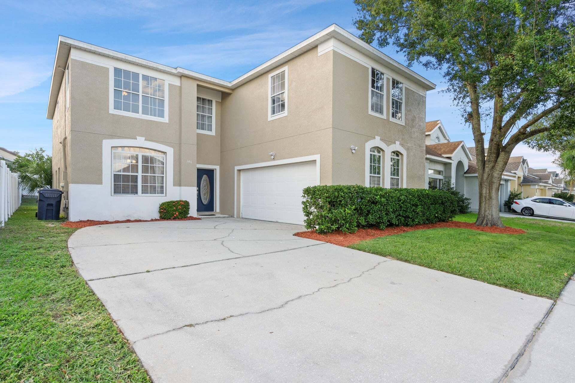 A two-story house with a garage, a driveway, and a well-maintained lawn.
