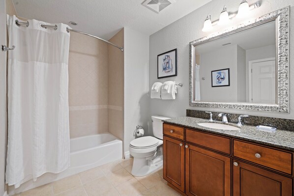 A bathroom with a shower, toilet, sink, and vanity.