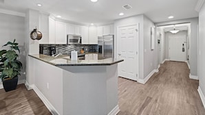 A modern kitchen with white cabinetry, a granite countertop island, stainless steel appliances, and a potted plant. - Bk0203 Villas South Preserve (Kissimmee)