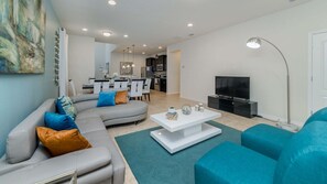 Een moderne woonkamer met een grijze modulaire bank, een witte salontafel en een tv-meubel.