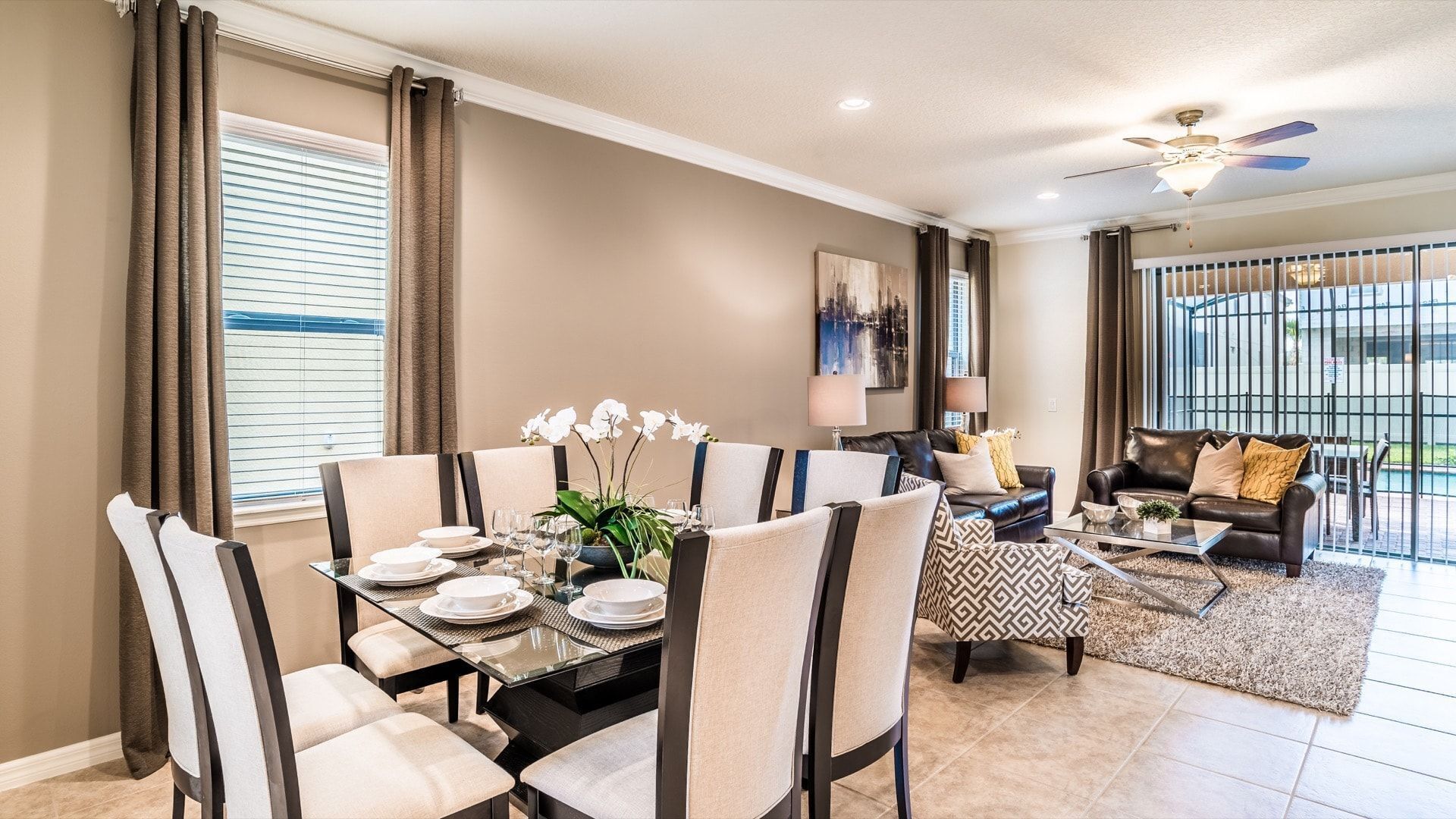 A dining area with a glass table, chairs, and a plant. There is a living area with a sofa and a coffee table.