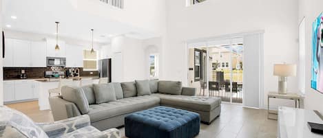 Amplia sala de estar con un sofá modular, un reposapiés azul y un comedor con mesa y sillas.