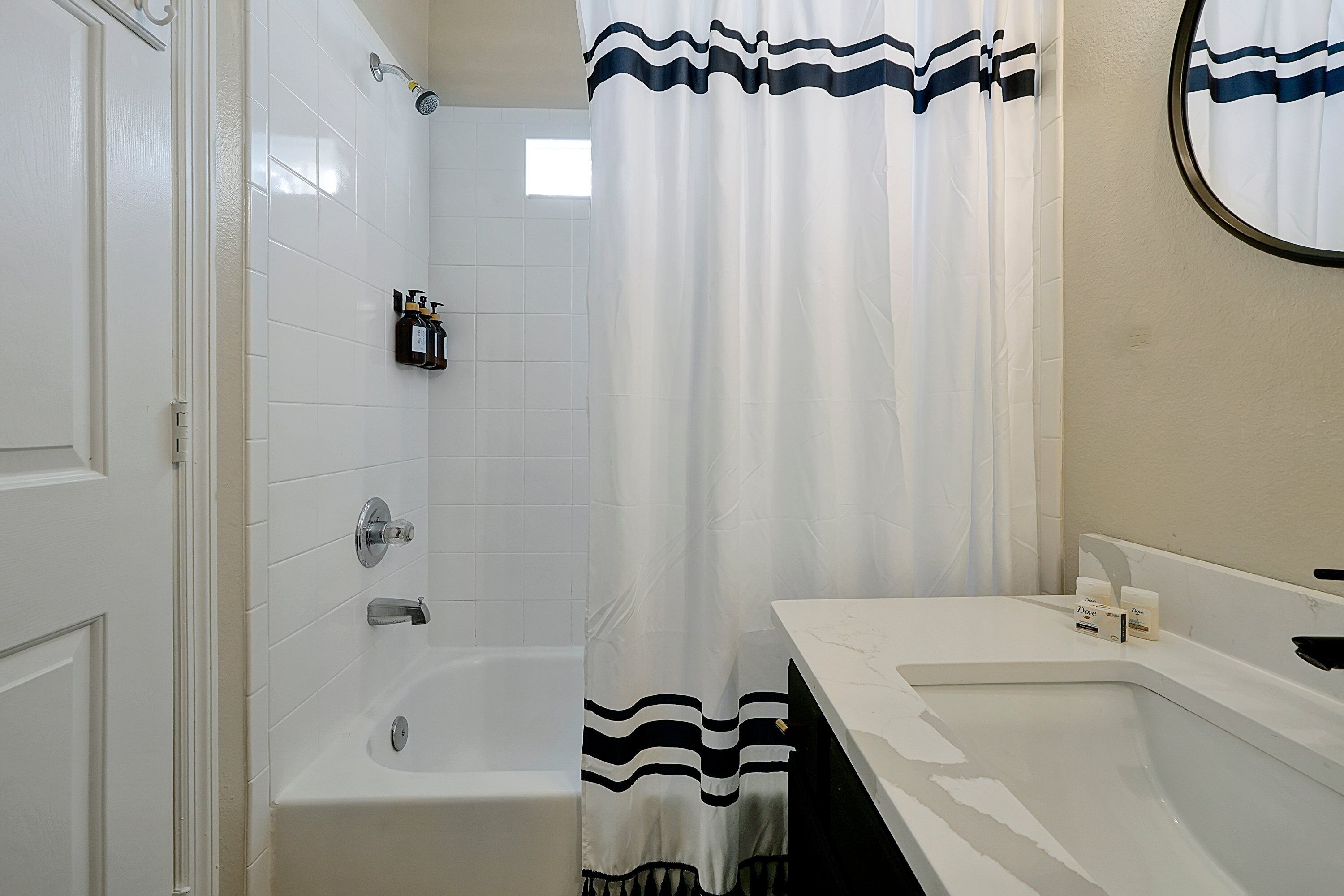 A bathroom with a bathtub, a sink, and a shower curtain with a striped pattern.