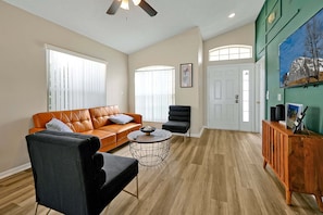 A living room with a sofa, armchair, coffee table, and a cabinet. - Pet-friendly Home w Pool Near Disney & Champions Gate (Davenport)