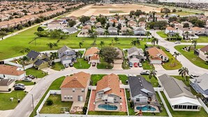 A residential neighborhood with houses, a swimming pool, and a large open field. - Pet-friendly Home w Pool Near Disney & Champions Gate (Davenport)