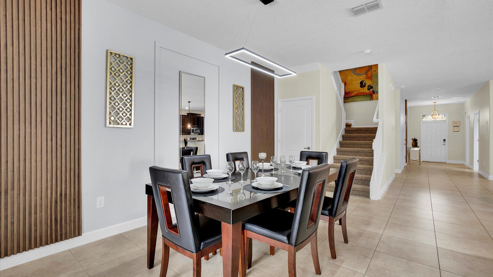 Een eetruimte met een lange tafel voor zes personen, aan weerszijden omlijst door twee houten panelen en een decoratief kunstwerk.