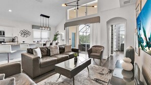 Een moderne woonkamer met een bank, salontafel en stoelen, een keuken met witte kastjes, en een eethoek met een tafel en stoelen.