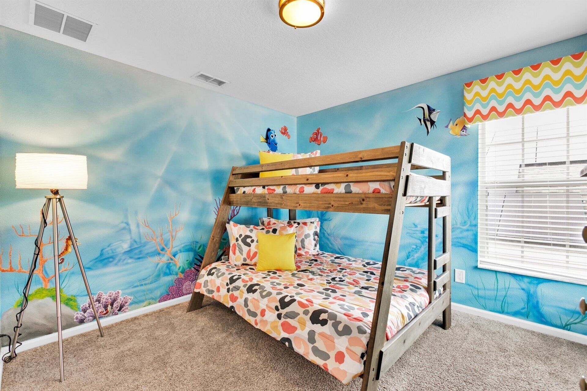 Habitación infantil con literas, un mural de paisaje submarino y una lámpara.
