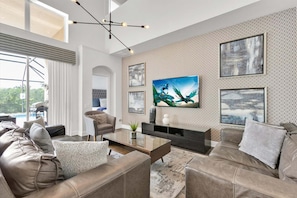 Ein modernes Wohnzimmer mit einem großen Fernseher, Ledersofas, einem Couchtisch und einer Wand mit Muster.