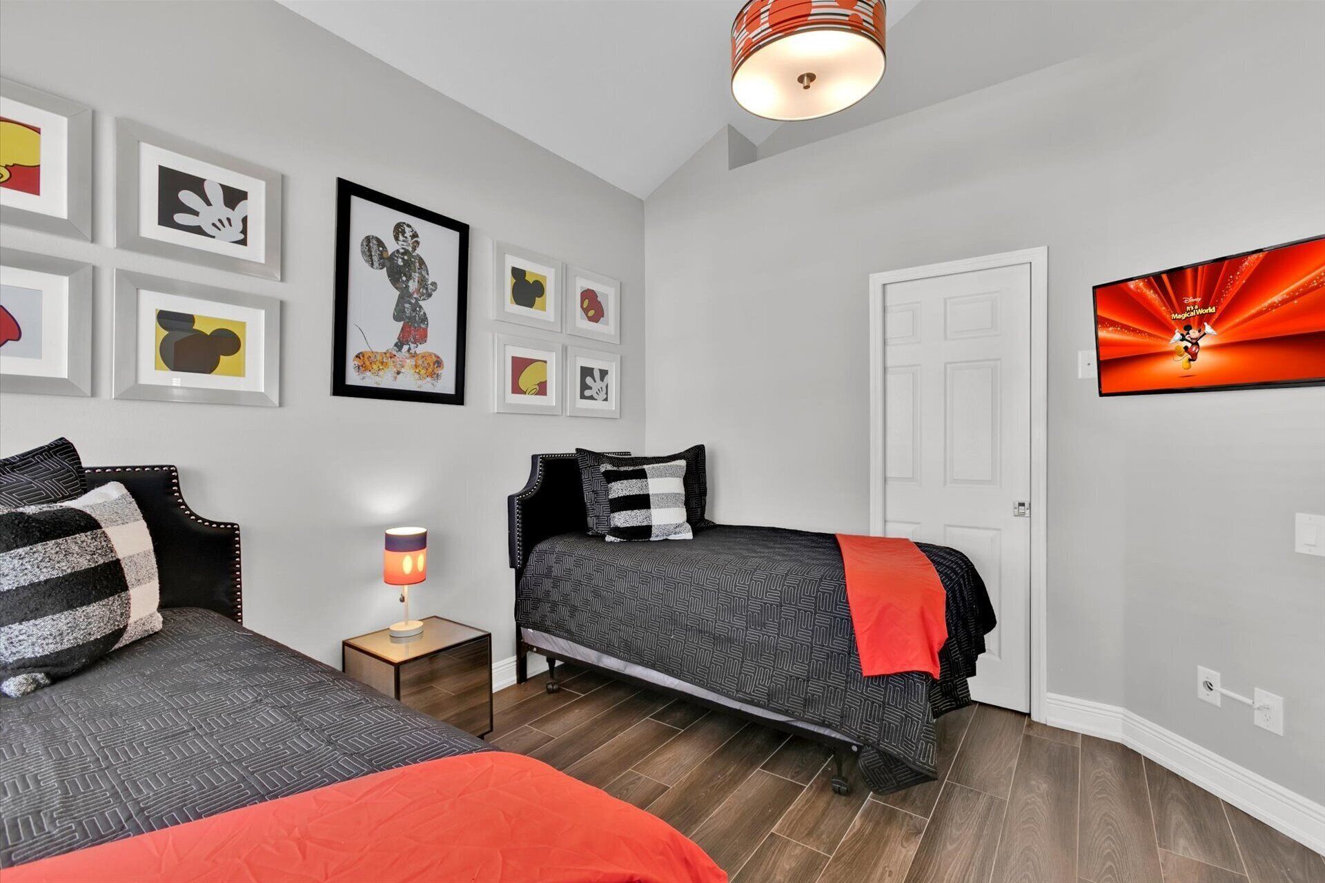 Un dormitorio con dos camas, una mesita de noche con lámpara y una puerta.