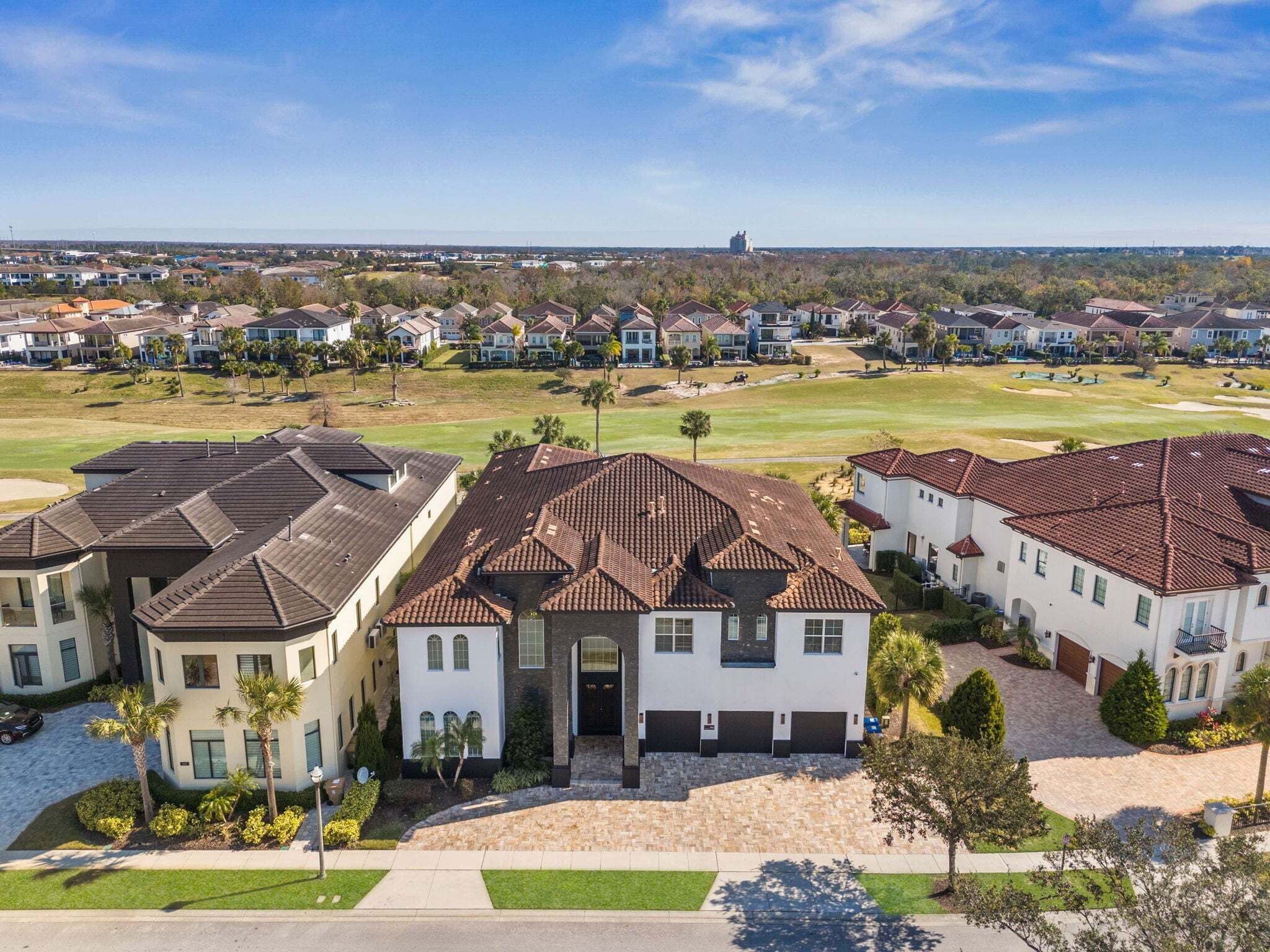 Un quartier résidentiel avec des maisons modernes, une pelouse bien entretenue et une vue lointaine sur les gratte-ciel d’une ville.