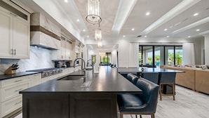 A modern kitchen with marble countertops, a central island, and bar stools. - Sg148t Eagle Cove (Kissimmee)