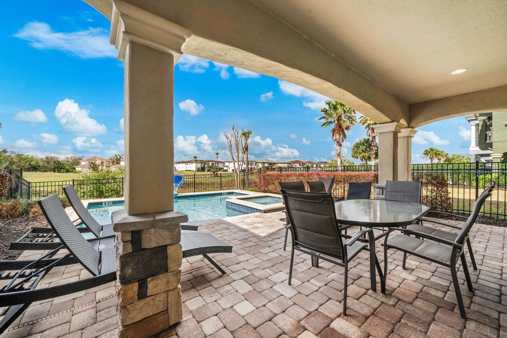 An outdoor patio with a pool, lounge chairs, and a table.