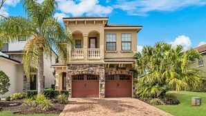 A two-story house with a stone facade, a balcony, and two garages. - Rc164p Fairway Fun Castle (Kissimmee)